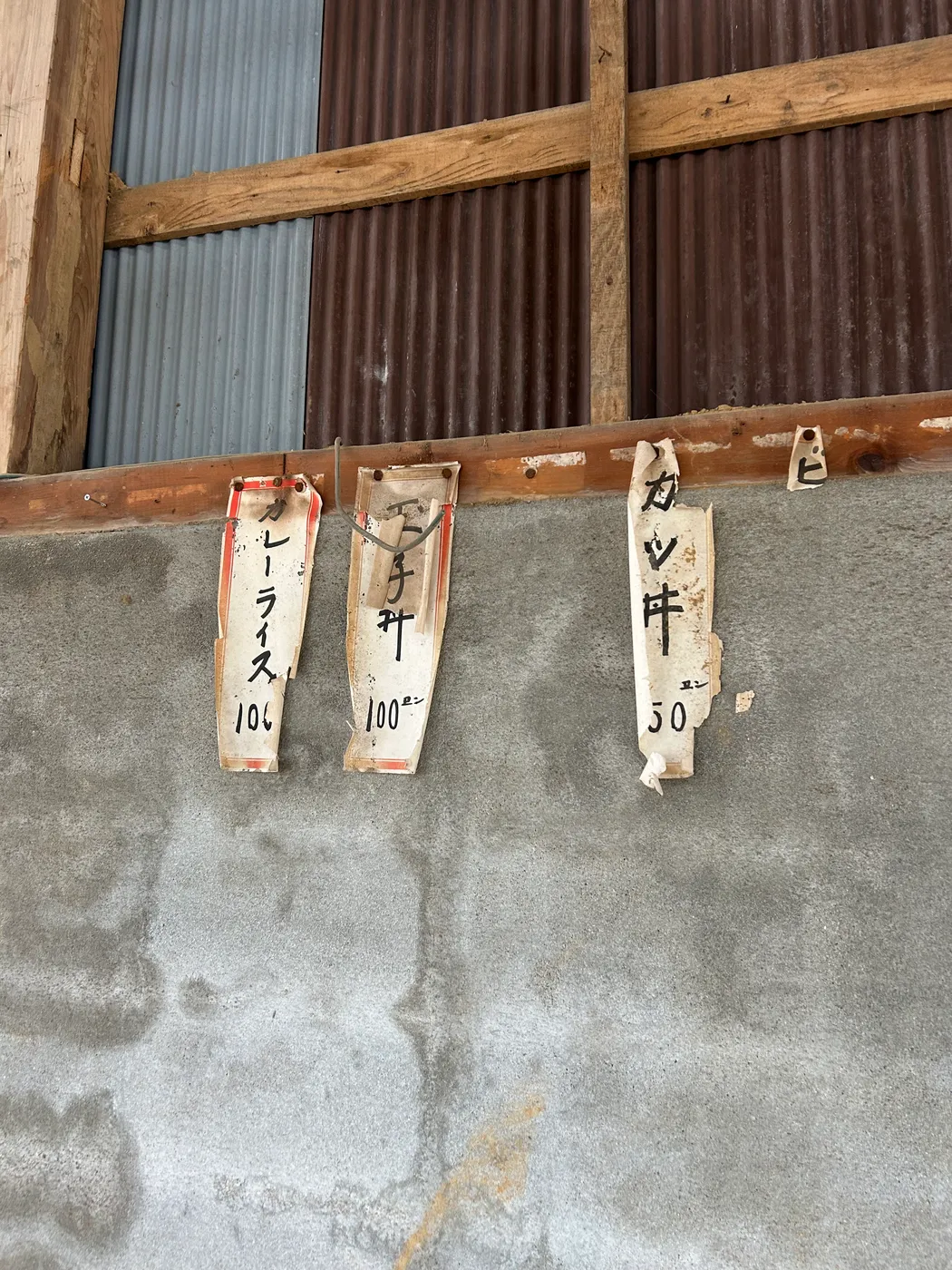 建物の壁に残る、手書きの古い品書き（カレーライス、玉子丼、カツ丼）