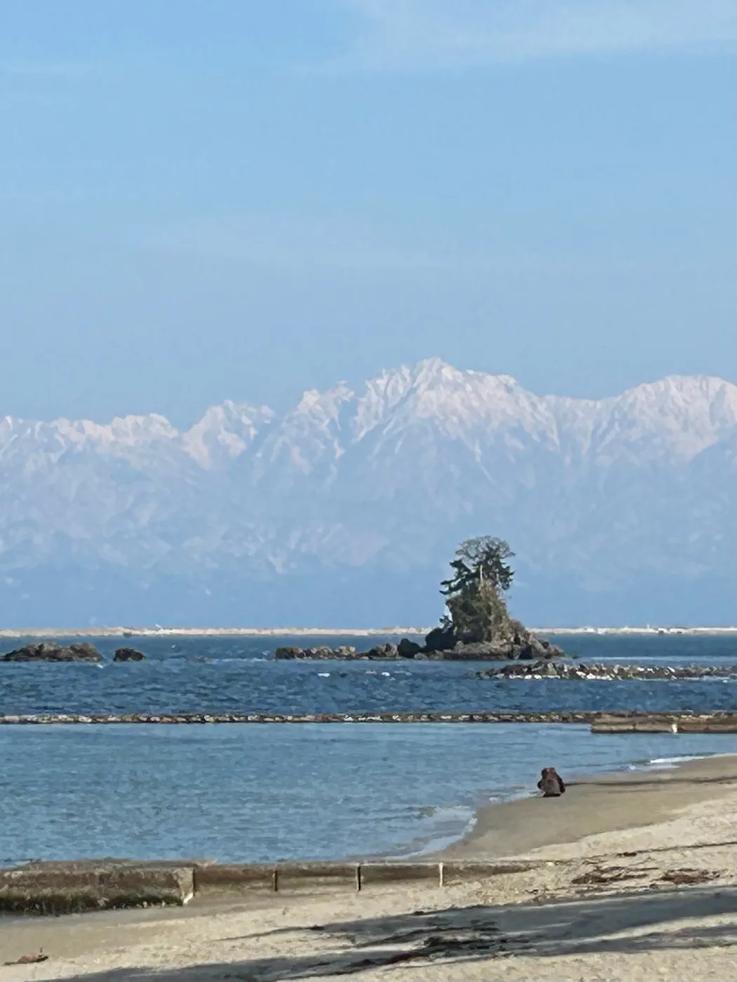 Meiwa rock on the Amaharashi Coast, with the snowy Tateyama mountains across the sea